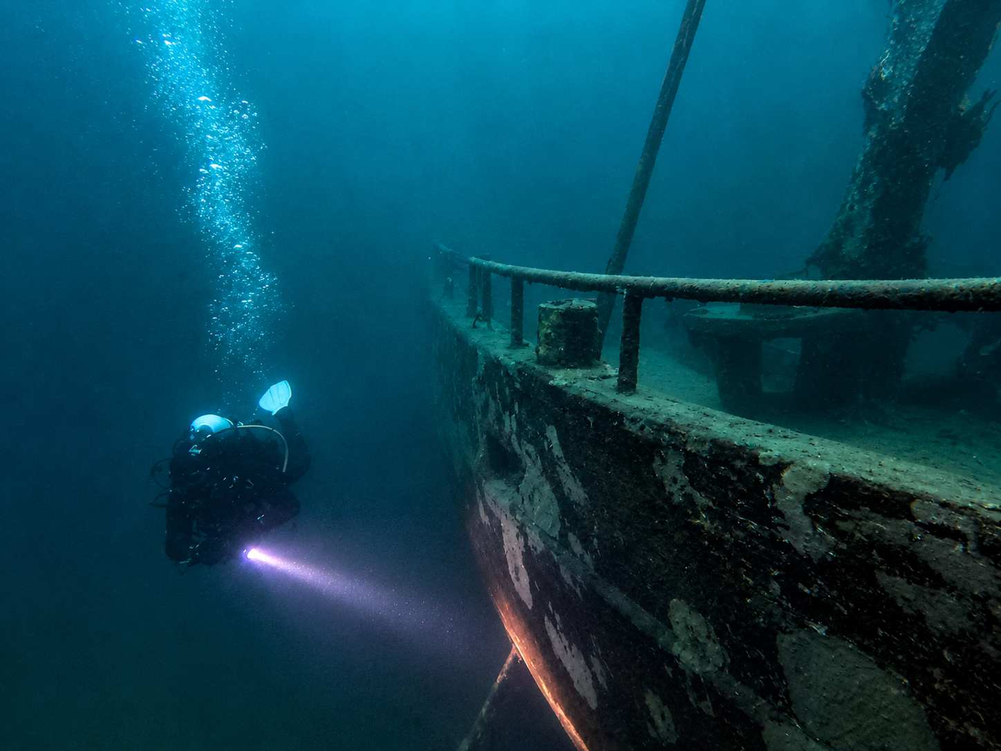 Taucher an einem Schiffswrack unter Wasser. Werbung für den PADI AOWD Kurs September 2026.
